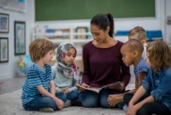 children and an adult sitting on the floor reading